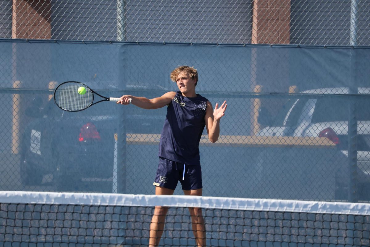 Senior Carson Alder hits the ball to the opposing singles player. 