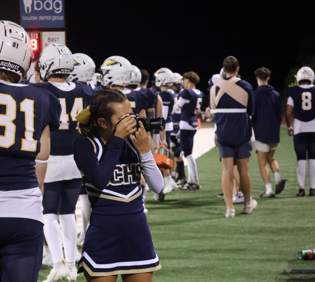 Senior Xochitl Skousen taking pictures of football for both Yearbook and Newspaper